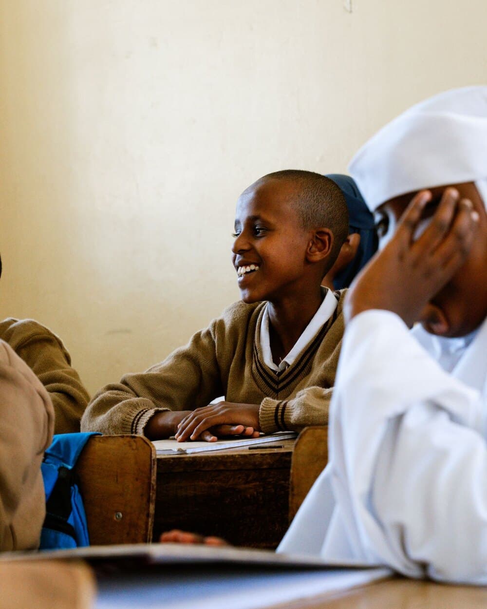 A pupil in a yellow headscarf smiling during a lesson